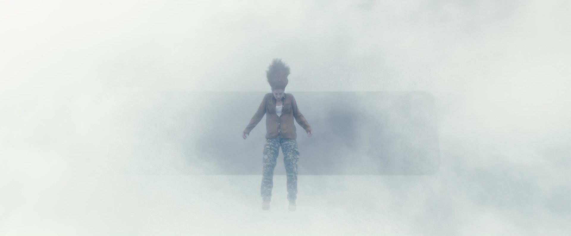A woman suspended in white mist, her hair floating upward as if gravity has shifted.
