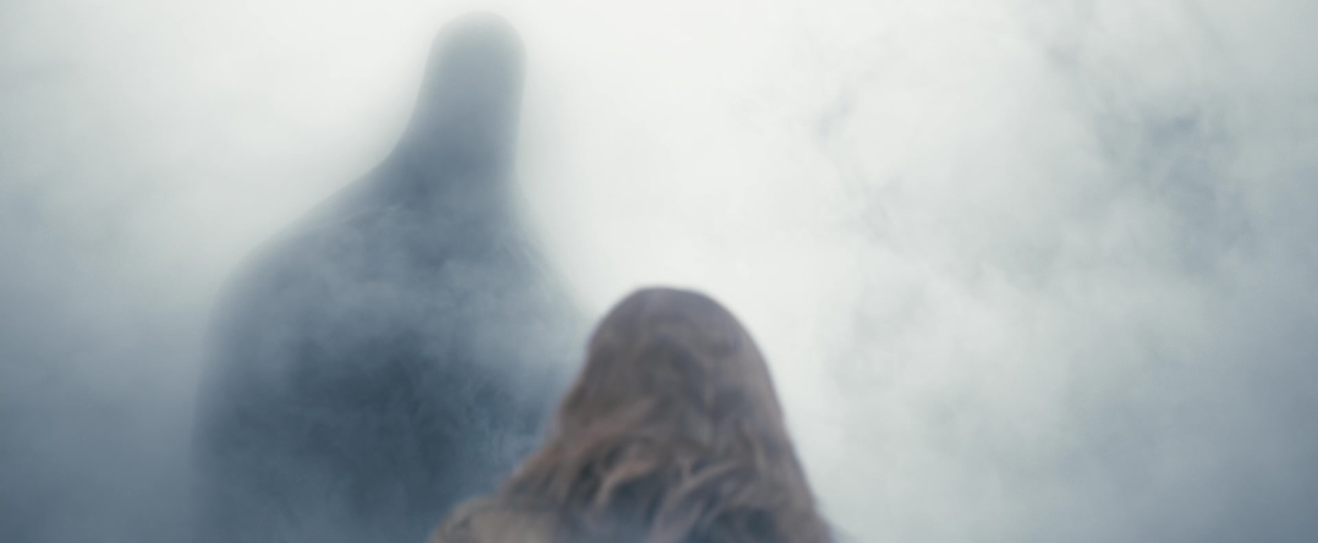 The back of a woman's head close-up as a tall shadowy alien figure leans toward her through thick white mist.